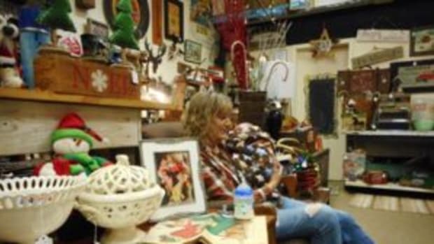 Terry Olson, owner of Time and Again Vintage in Dodgeville, Wisconsin, rocks her sister-in-law’s grandchild amid the displays while they both work at the store. Photo by Mary Glindinning
