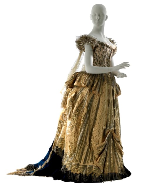 The yellow satin Electric Light dress designed by Charles Frederick Worth. It's decorated with glass pearls and beads in a lightning-bolt pattern. This dress was only one of several spectacular gowns that served to make the event the official start of Alva Vanderbilt's role as a leading socialite of New York. The dress is preserved at Museum of the City of New York.