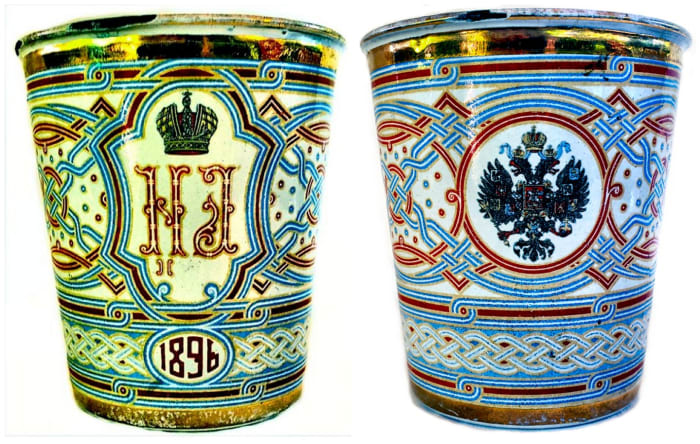The cup pictured here is an example of the beauty and artistic achievements that can be obtained with the use of vitreous enamel. This beaker was made for the coronation of Tsar Nicholas II and Tsarina Alexandra Feodorovna in 1896. One side of the cup displays highly detailed interlacing patterns and braiding with a central cartouche encircling the cyphers of Nicholas and Alexandra with the date of “1896.” The opposite side of the cup illustrates the Romanov eagle. It was meant to be known as the Coronation Cup, but as a result of its tragic history, it is more commonly known as the Khodynka Cup of Sorrows, the Sorrow Cup or the Blood Cup. During the coronation celebration on May 18, 1896, gifts, including this beaker, were distributed to the crowd of more than 500,000 gathered at Khodynka Field when a rumor spread that each of the cups contained a gold coin. The crowd surged forward and in the ensuing stampede, more than 1,000 people were trampled to death. The Tsarina henceforward referred to the souvenir as “the cup of sorrows.” The rim of this cup is chipped in two places, which shows the underlying copper. My sister has a collection of these beakers and almost each one has similar damage, which may simply be the result of 123 years of existence, although one can’t help but wonder if the damage is the result of the tragic circumstances of the day.