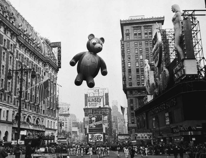 A teddy bear flies high and looks down on the crowd in 1949.