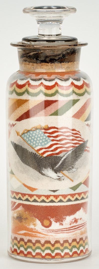 Patriotic sand art bottle, dated 1889, filled with multicolored, layered sand in decorative stripe, swag and diamond patterns, one side with a vignette of a spread-winged eagle and 36-star American flag, the alternate side with a detailed floral vignette including forget-me-nots, roses and pansies, 6-5/8" h. This sold at auction for $55,000 against a high estimate of $12,000.