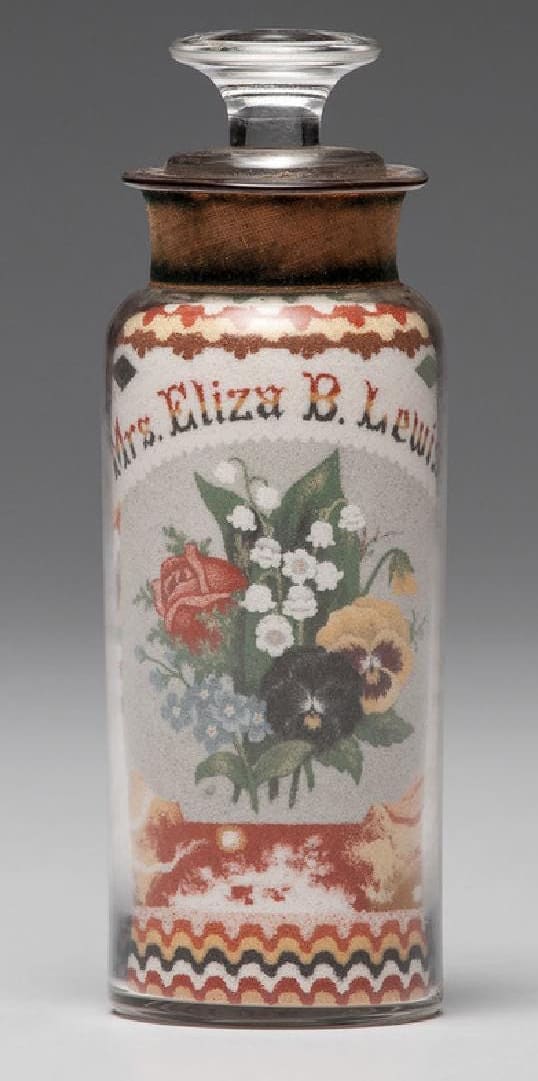 A Clemens' sand bottle with an American spread-winged eagle underneath a flag of thirty-six stars on one side, the other having a floral bouquet below the name Mrs. Eliza B. Lewis, decorated with layered, colored sands in geometric patterns, 6-3/4" h; $132,000.