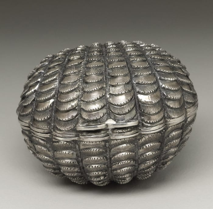 A Victorian silver nutmeg grater in a scalloped cockle shell form, Hilliard & Thomason, Birmingham, England, 1865-66, about 2” l; $2,390.