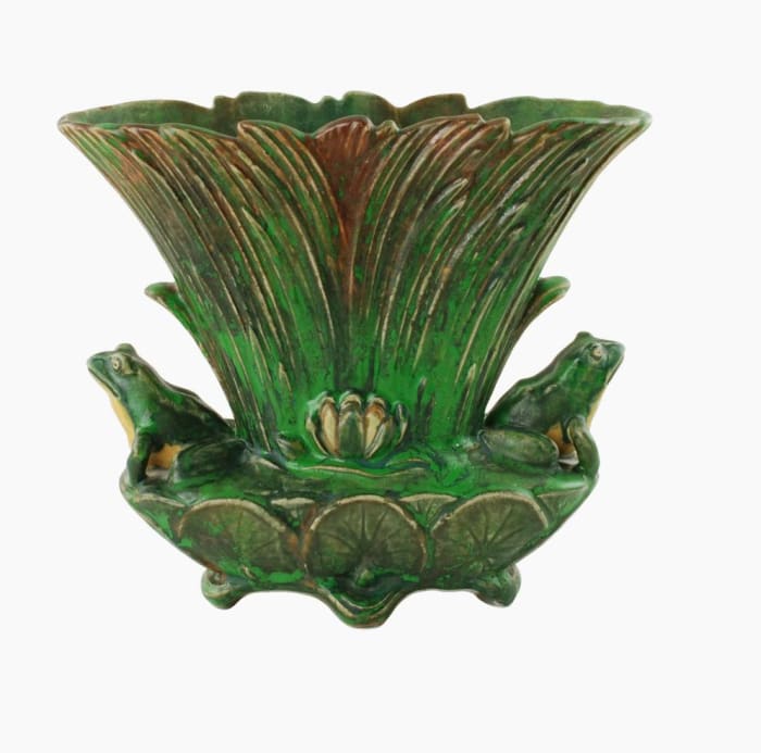 The authentic 1920s’ fan-shaped Coppertone vase, with a series of overlapping reeds and featuring two lifelike dimensional frogs that are seated at either side of the reeds. The front and back of the piece bear molded cream-colored water lily flowers located at the center, while the lower portion is decorated in overlapping  lily pads. The piece is elevated on four feet; $1,250.