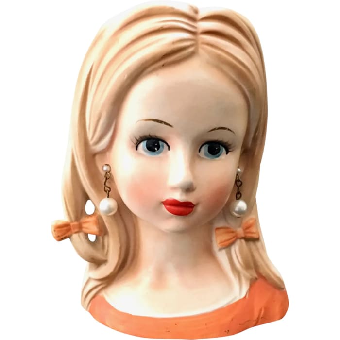 A hard-to-find teen-age girl head vase by Relpo, with blonde hair, orange dress, pearl earrings and two hair bows, late 1950s-60s, stamped “A639,” 5-1/2” h on a 3-3/4” x 2-3/4” base; $195.