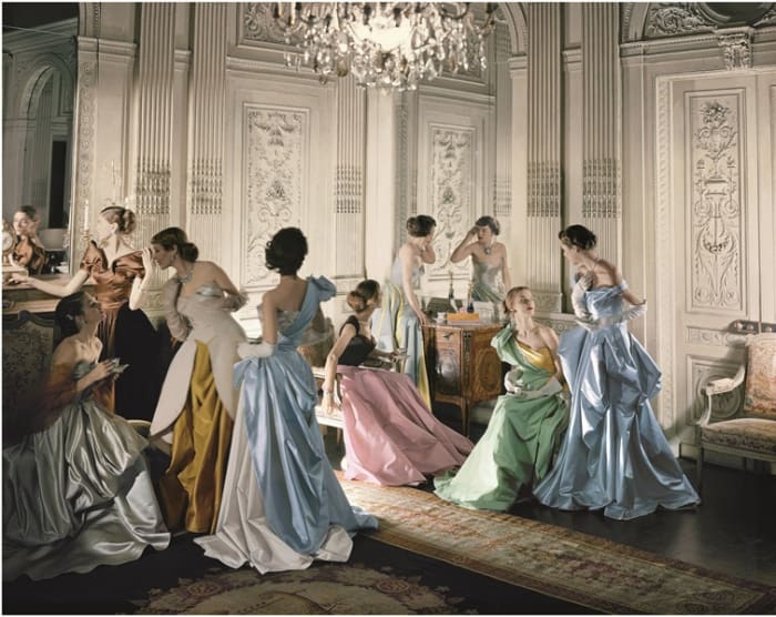 A famous Cecil Beaton photo from 1948 of nine models, including Marilyn Ambrose, Dorry Adkins, Carmen Dell'Orefice, Andrea Johnson, Lily Carlson, and Dorian Leigh, wearing various gowns by Charles James while posing in French & Company's eighteenth century French paneled room.