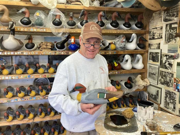 Decoy carver Charles Jobes with a green-winged teal drake decoy in his Havre de Grace workshop.