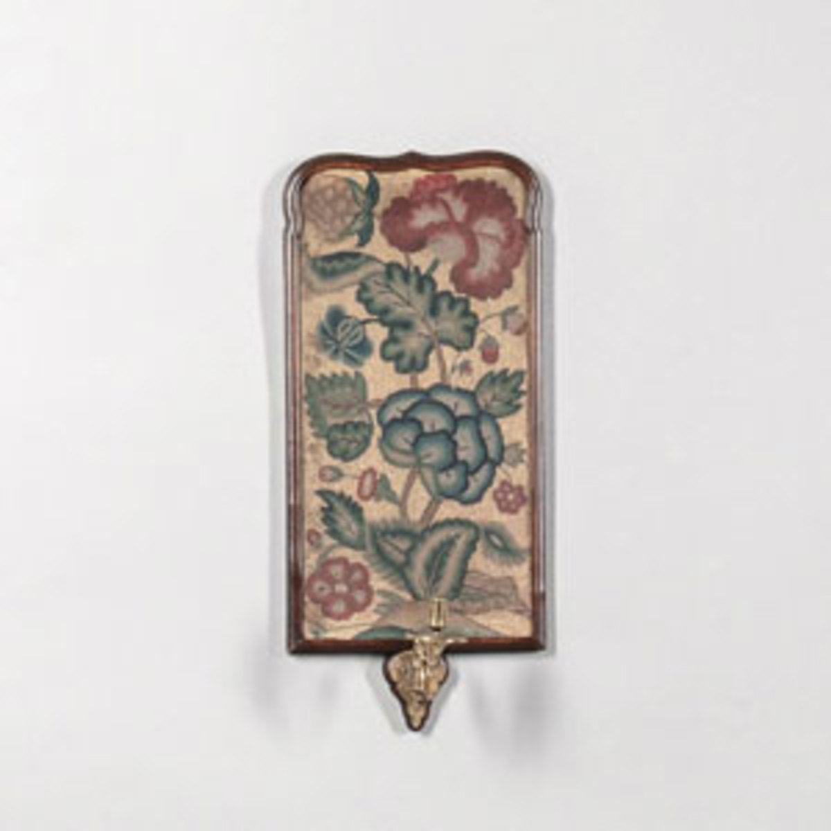  Needlework candle sconce, England, 18th century, the rectangular "sconce" with a framed floral needlework picture supporting a single brass candle socket on a scrollwork branch, 22" h, 9-3/4" w. Sold for $6,765 - far above its estimate of $800-$1,200. Image courtesy of Skinner Auctioneers and Appraisers