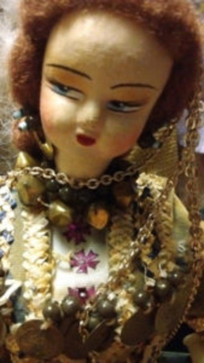 Close up of a Vintage Greek doll with silk painted face over a mask. She wears a traditional costume with Dowry Coins