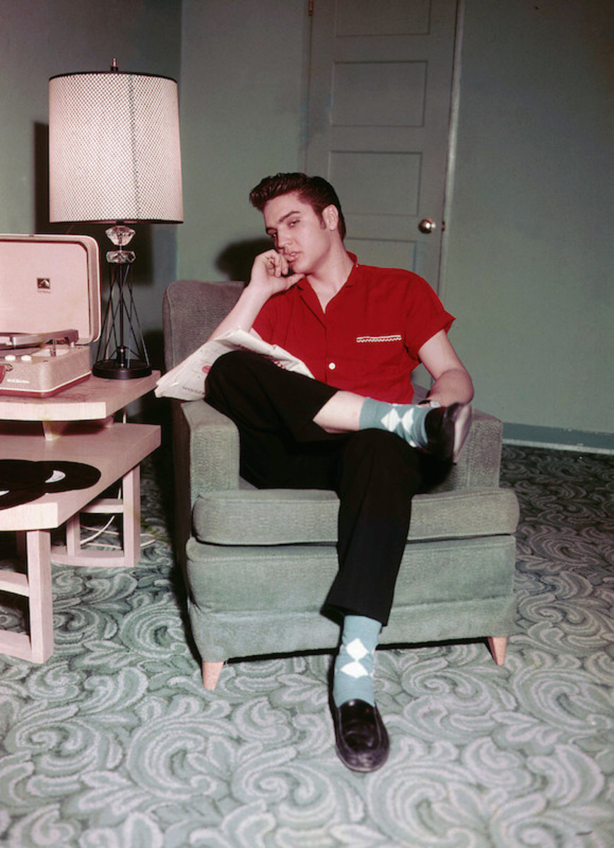 Elvis looking casual and cool while relaxing at home in 1956. Dig those argyle socks and penny loafers – and the RCA Victor record player.