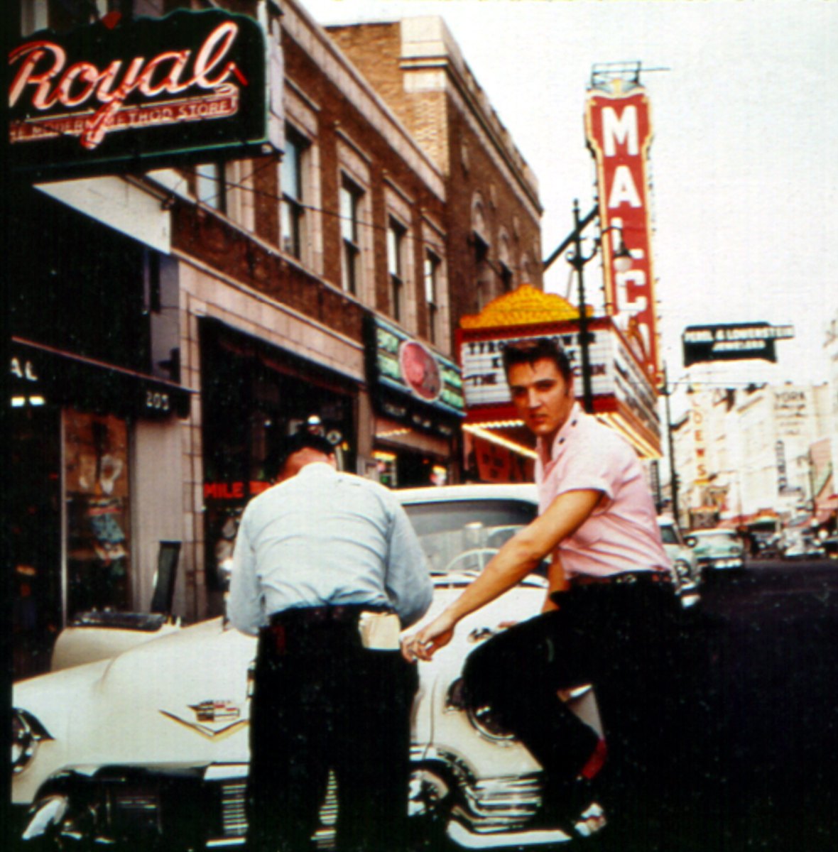 Elvis even looks stylish while getting a parking ticket in Memphis in 1956 outside of Jim’s Barber Shop. I love that he’s wearing pink and that the red touches on his belt match his red socks.