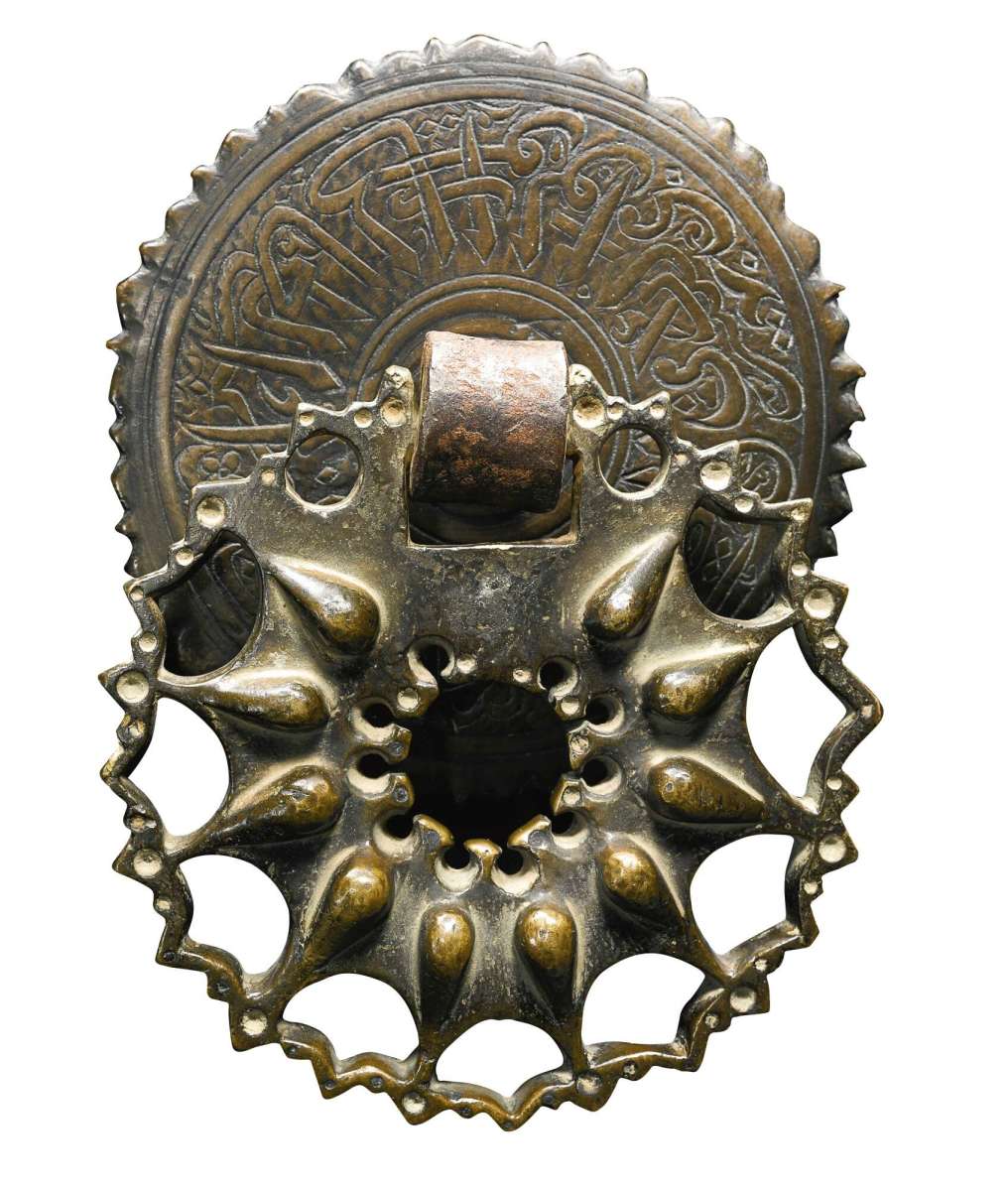 A Mamluk bronze door knocker, probably Egypt, 14th century. It is made of two separate sections, has a straight hook for hanging, and the plate has an engraved calligraphic band; $8,745.