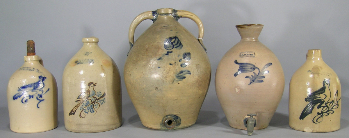 Various stoneware jugs are up for bid, including the rare 19th century Julius Norton cobalt-decorated stoneware jug shown in the middle; ovoid, Bennington, VT, 5-gallon, two handled, having a cobalt flower decoration on the front and cobalt decoration at each end of the handles, 17-3/4” h; estimate: $3,000-$5,000.