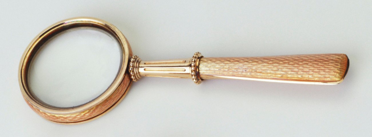Miniature magnifying glass, c. 1900, pale yellow guilloché enamel frame and handle, fluted gold and beaded collar; 2-3/4” x 1” x .2”. Even for the most minute and barely functional objects, such as this magnifying glass, Fabergé’s level of craftsmanship and quality of finish of objects was always of an extremely high standard. This was likely acquired by Queen Alexandra, c. 1900.