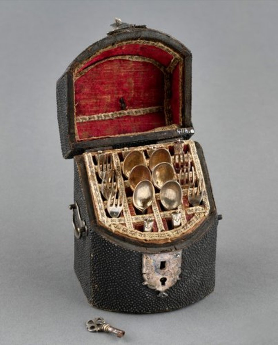 This black rough leather box with sloping hinged lid and box front contains a set of silver miniature cutlery of six knives, six spoons and six forks, and a silver key; 3-1/2” x 2-1/2” x 2”. This was acquired by Queen Mary.