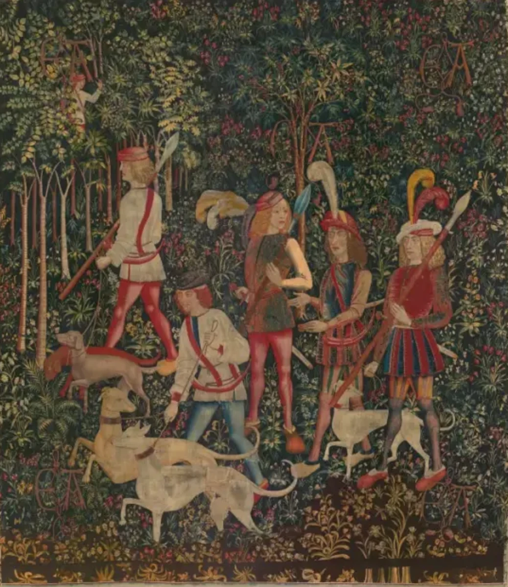 Tapestry 1: Hunters Enter the Woods. This tapestry of a group of noblemen and hunters, like “The Unicorn in Captivity,” is set against a millefleurs background: a field of dark green spangled with blossoming trees and flowers. Of the 101 species of plants represented, 85 have been identified, including the prominent cherry tree behind the hunters and lush date palm in front of the sniffing hound. The cipher “AE” that is woven into each of the tapestries — and repeated here five times — alludes to their original owners, who remain unknown.