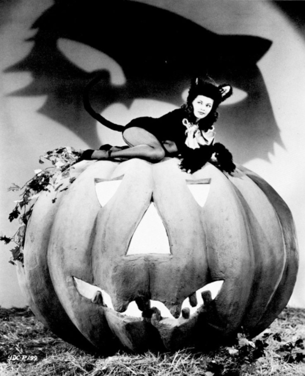 Famous for her betrayal of vampire Lily Munster, actress Yvonne De Carlo perches on top of a giant pumpkin as another mischievous feline.