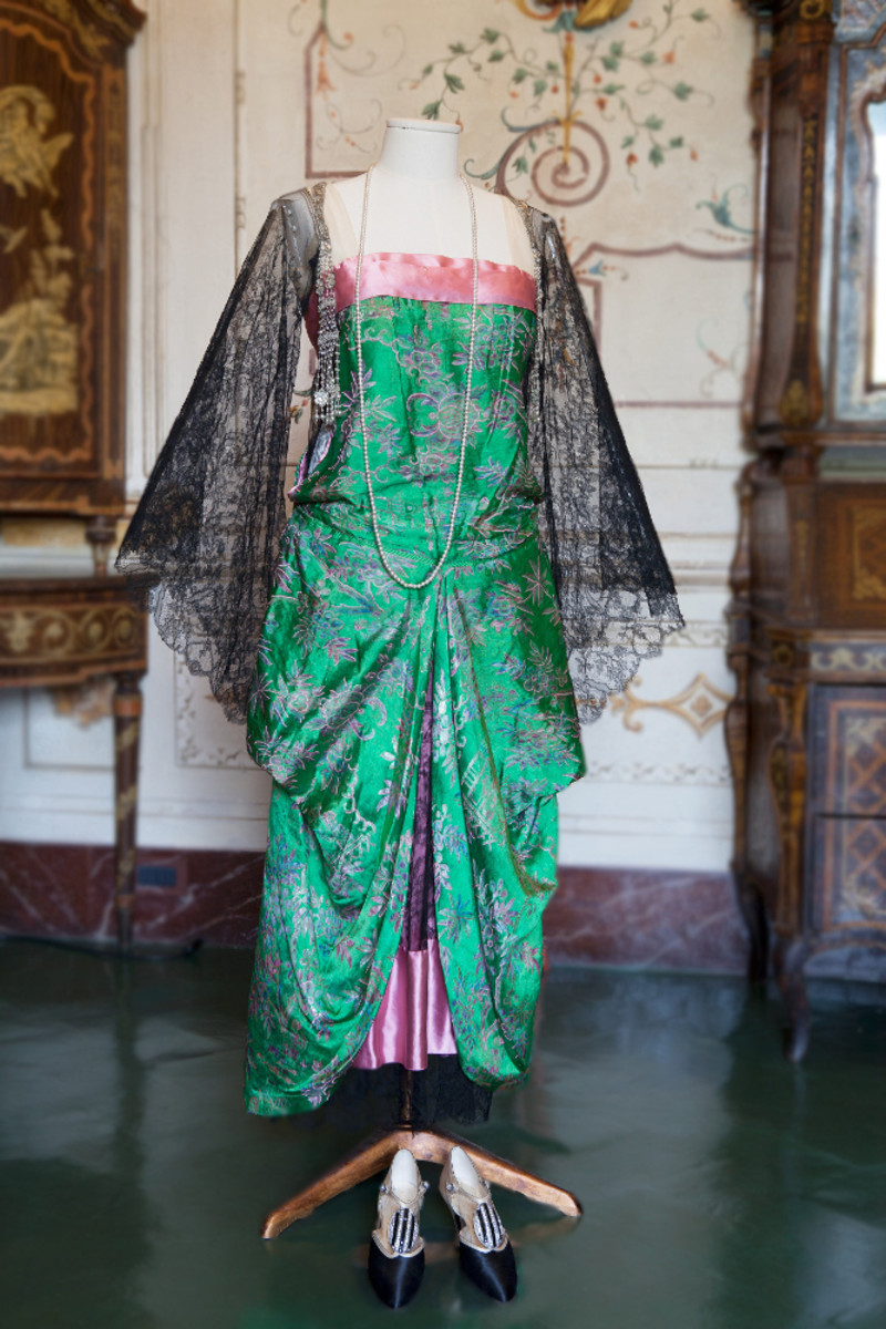 Hortense’s passion for the Asian world was an interest that began when she was a child in Chicago, and many of her Callot Soeurs' dresses show influence from Chinese costumes. This pink and green silk dress from the 1920s is a more obvious example of this. The cut (emphasis on the black lace bat wings and loose-fitting design) and embroidered details of the fabric (which is likely directly from China) are examples of how the Chinese style influenced the design. Passementerie tassels composed of rhinestones, pearls and beads that hang from either shoulder.