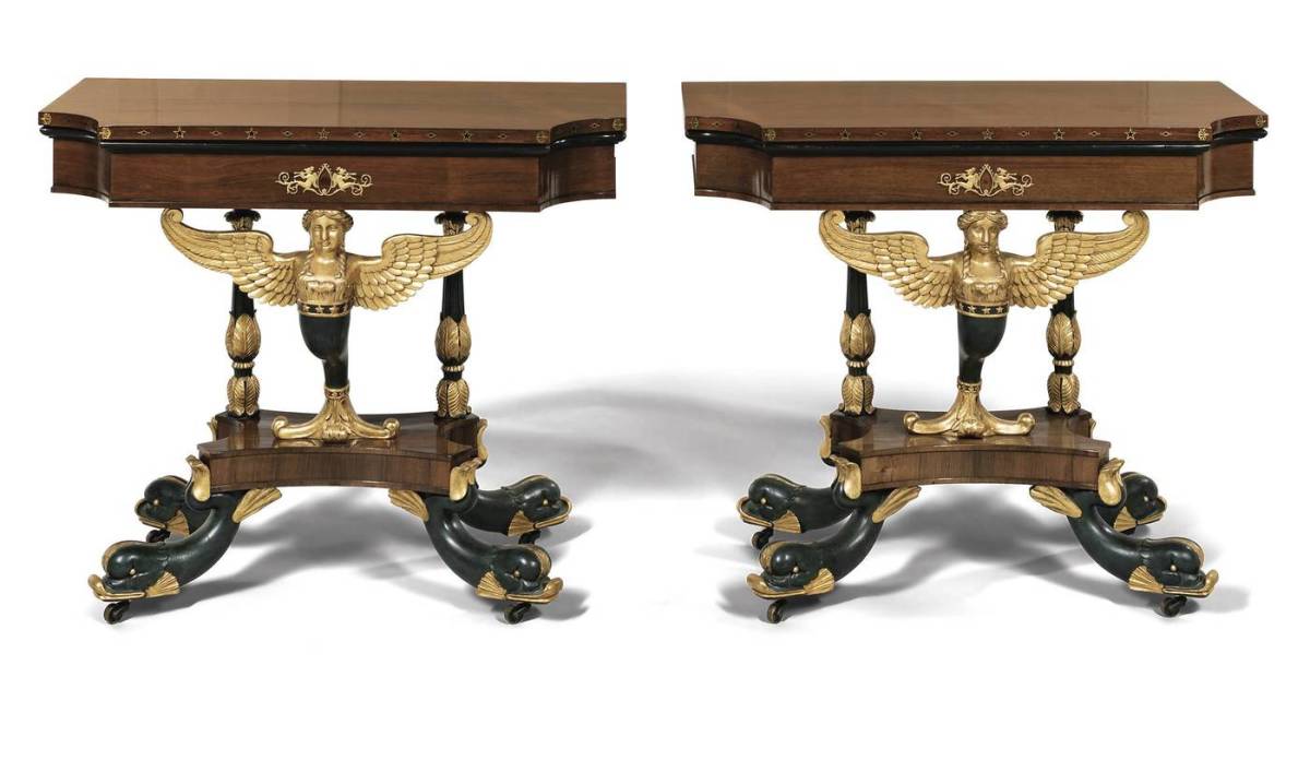 Important pair of classical rosewood, gilt-gesso, and vert antique brass-inlaid card tables, Charles-Honore Lannuier, c. 1815. Each with a shaped hinged top with concave corners, the edges with brass inlaid stars, diamonds, and anthemions and ebonized molding above conformingly shaped friezes centering ormolu mounts depicting nymphs playing panpipes, on a carved gilt-gesso and vert antique caryatid winged female figure with braided hair and a star-banded waist continuing to a scrolled foliate support. Estimate: $100,000-$150,000.