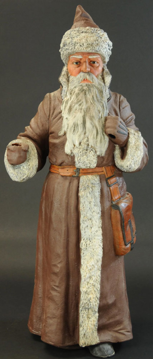 A superb and seldom seen terracotta Belsnickle figure, wearing a long red robe outlined in white that blends in with his substantial white and gray beard, his fur-trimmed cap sits atop of a well-sculpted face; 45" h. This sold in November for $14,000.