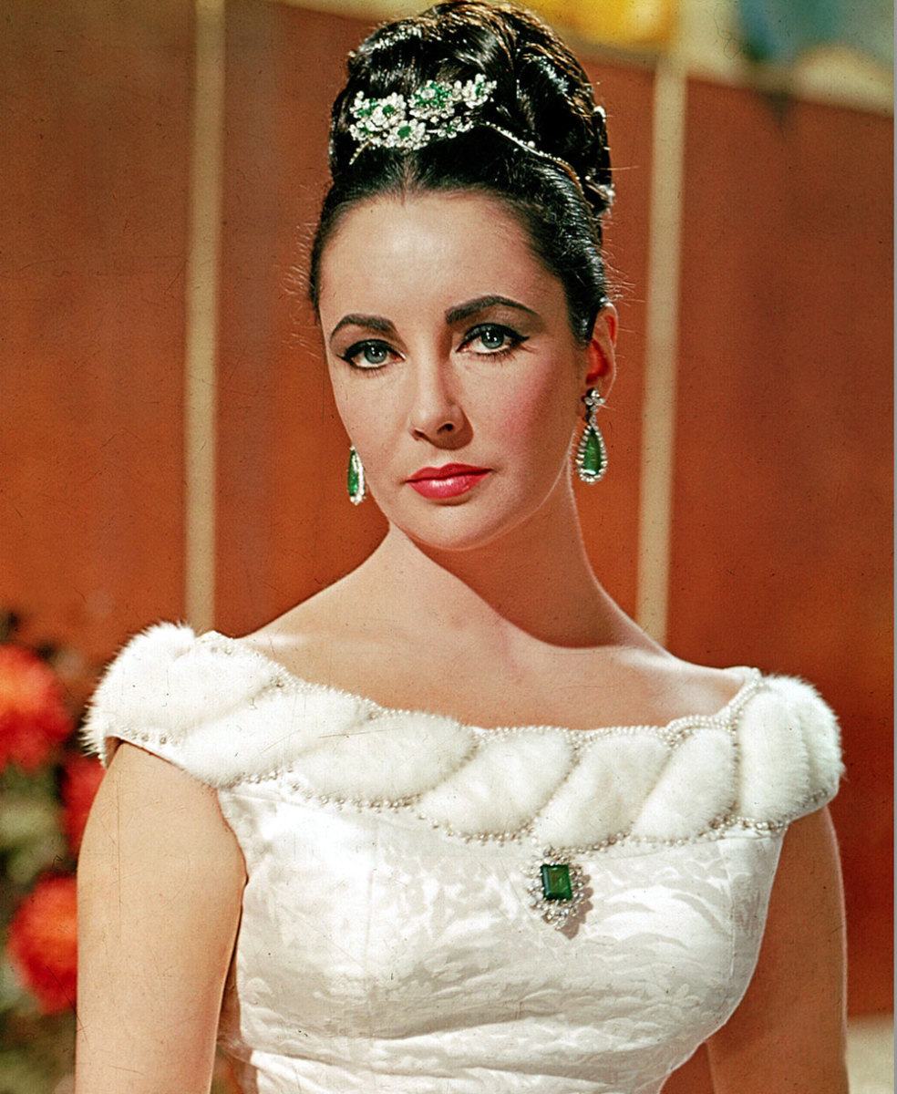Elizabeth Taylor resplendently wears some of her emerald and diamond pieces in the 1963 movie, "V.I.P.s," that were given to her by her fourth husband Eddie Fisher (the flower brooch she is wearing in her hair) and her fifth husband Richard Burton (the pendant earrings and brooch he gave her for their engagement). All are by Bulgari, one of her favorite designers.