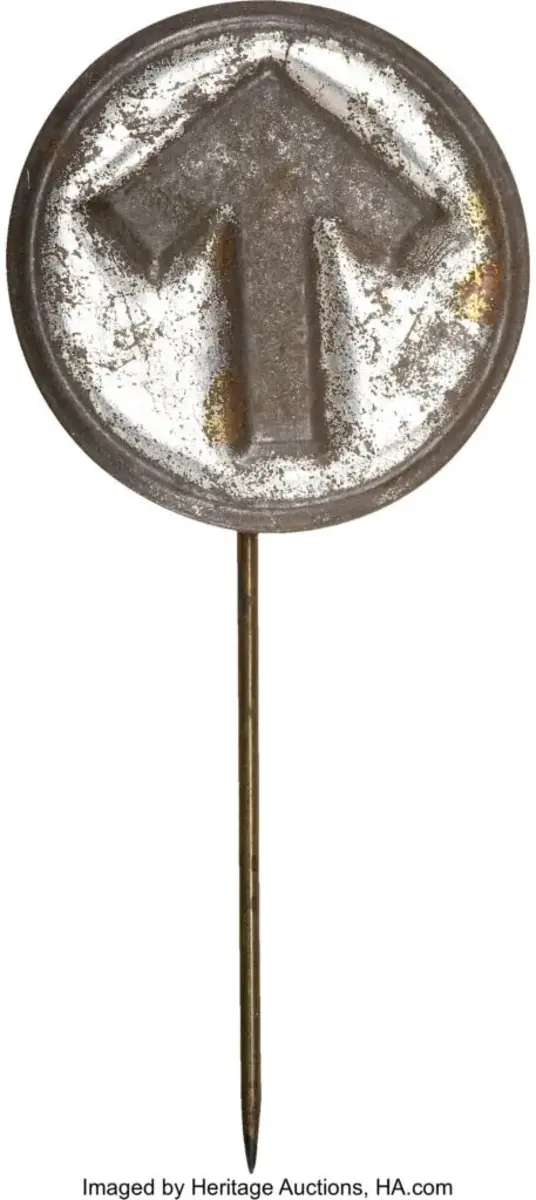 This pressed-metal stick pin is English in both manufacture and distribution. Sylvia Pankhurst, the artist-daughter of Emmeline Pankhurst, one of the founders of the W.S.P.U. (Women’s Social and Political Union), designed the famous Portcullis or Holloway prison brooch which was based upon the portcullis symbol of the House of Commons. It featured a superimposed arrow in purple, green, and white, the colors of the W.S.P.U., over the Commons gates. These brooches were given only to those who went to prison for the cause, although the design did appear on teacups and postcards sold to the public. The arrow, which represented the obstructions at the bottom of the gate, became an iconic symbol in its own right, and it appeared on several varieties of hatpin without any explanatory wording, the symbol becoming well known. One also finds this exact symbol on photographs of prison garb worn by suffragists. This is the first known example of the arrow on a stick pin. Loss to finish on the high spots, else very good. Sold for $239.