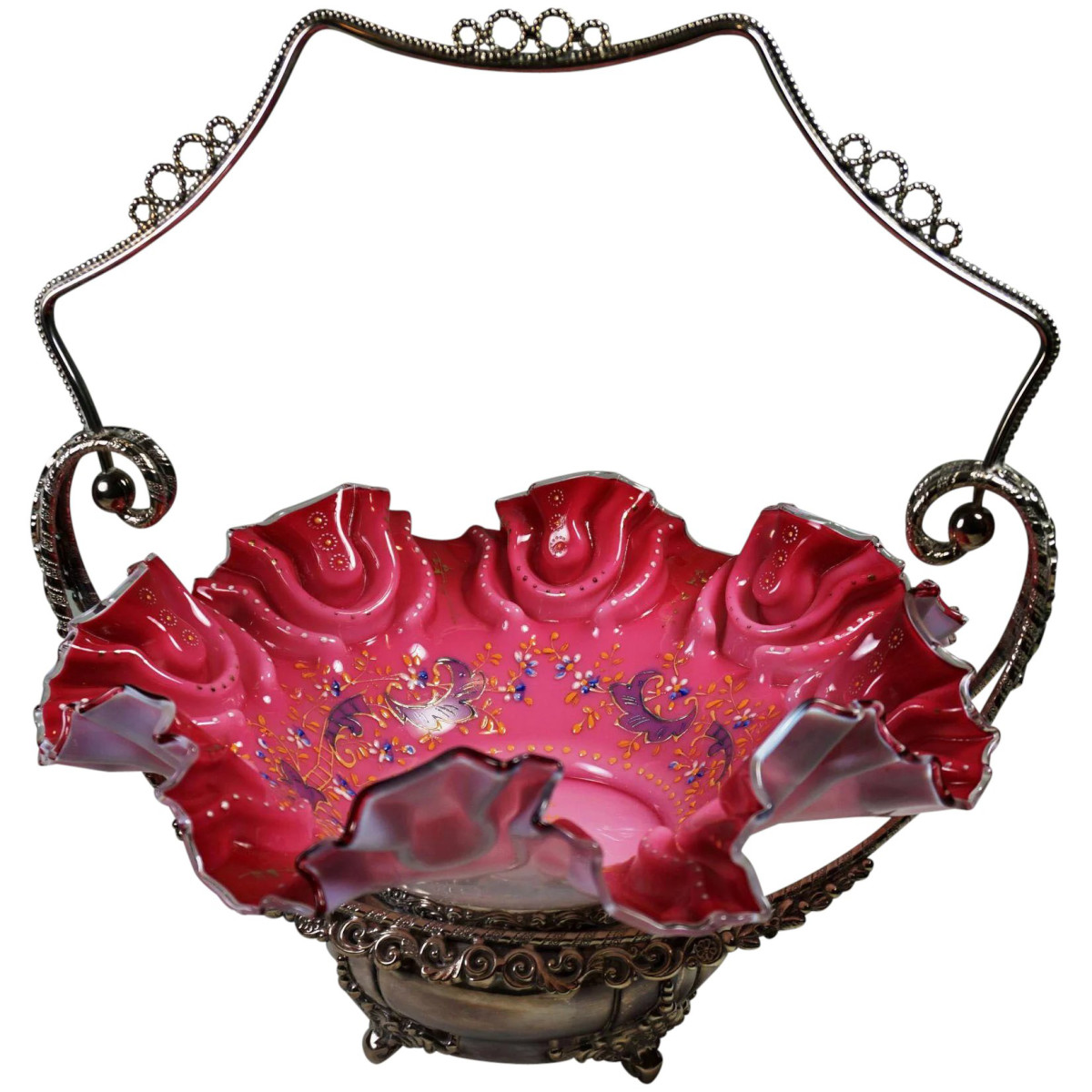 Victorian bride’s basket by Meriden Silver Plate Company, Meriden, Conn., cranberry and opal glass, circa 1880s, molded floral influenced decorating patterns around the bowl, embellished with hand-enameled Rococco designs and floral motifs; $645.