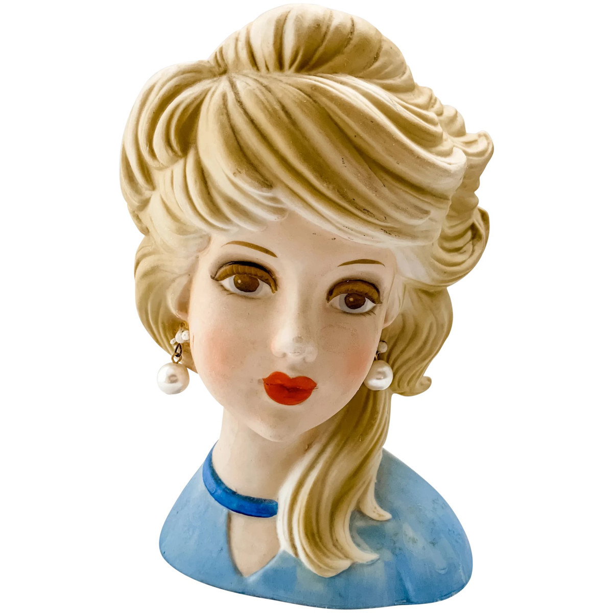 Elusive Inarco E-6210 head vase dubbed the “Ghost Girl” or “Ghost Sister” by collectors because of her light matte coloring and is a scarce find. Circa 1950s-60s, she has a medium-blue bodice with a deeper blue narrow collar topping a peek-a-boo V in the front of her gown, large pearl drop earrings, side-swept blonde hair, mark reads “Inarco® E6210” with an elliptical world map, 7” h, base is 4-1/4” x 2-3/4”; $275.