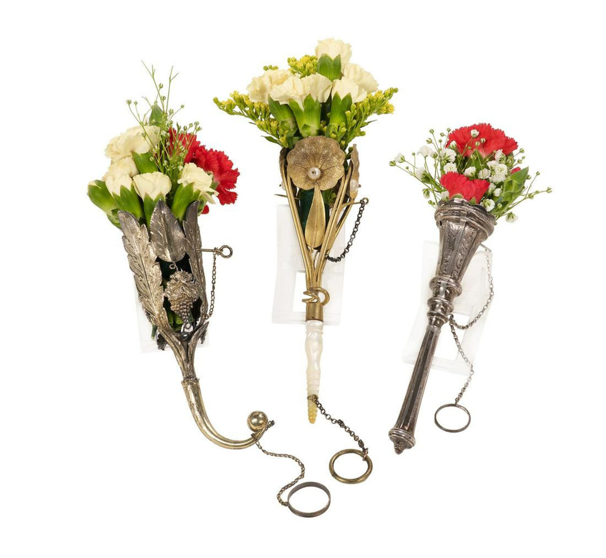 Lot of three Victorian tussie-mussies, late 19th century, each with a chained pin and finger ring: gilt metal with embossed lily pads centered by a faux pearl, turned nacre handle, 6-1/4” l; silver with tapering paneled cup and handle, engraved scrolls, 5-3/4” l; and gilt metal with embossed acanthus fronds and grape clusters, scroll handle with ball finial, 5-1/2” l; $950.