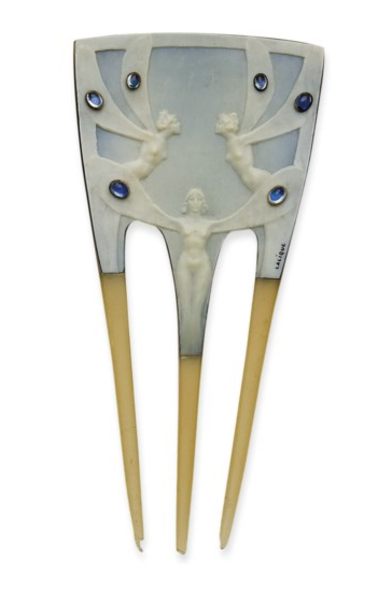 Winged Women: The head of this comb, in horn, is covered with a bone plate on which are engraved three winged, naked women, each of their wings adorned with a cabochon of blue glass; the three teeth are in blond horn; 3-1/2" h, about 2-1/2" at the widest point. This sold at Christie’s in 2008 for $30,723.